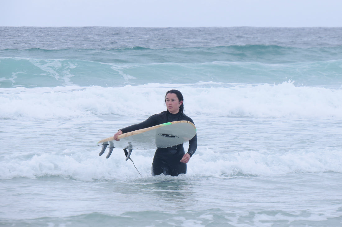 Lucy, holding her surfboard in the waves.